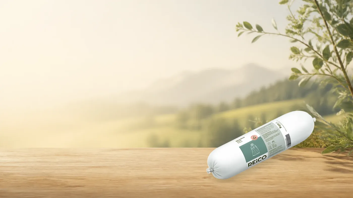 MAXiDOG Cura Pferd, 600 g – offizielles REiCO Produktmotiv in warmer Naturkulisse mit heller Holzfläche.