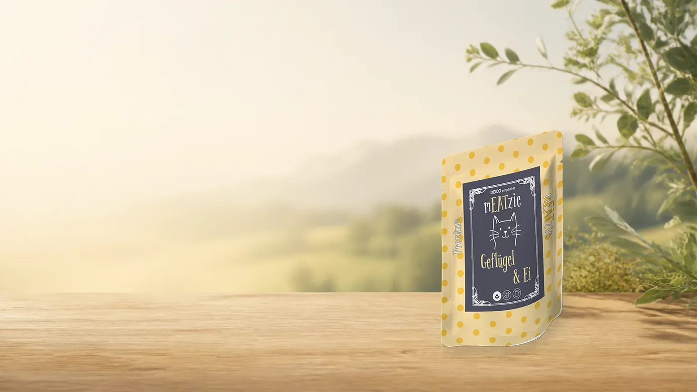 mEATzie Geflügel & Ei – offizielles REiCO Produktmotiv in warmer Naturkulisse mit heller Holzfläche.