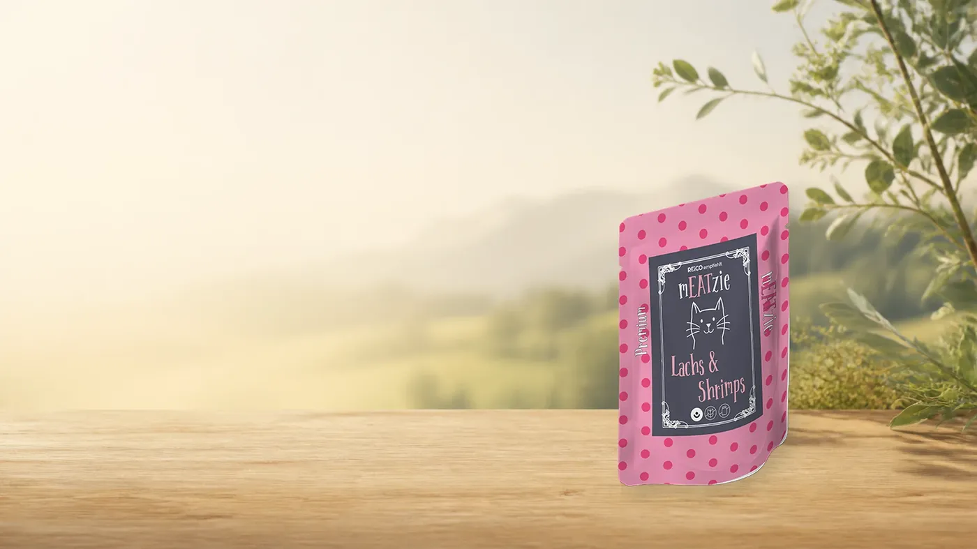 mEATzie Lachs & Shrimps – offizielles REiCO Produktmotiv in warmer Naturkulisse mit heller Holzfläche.